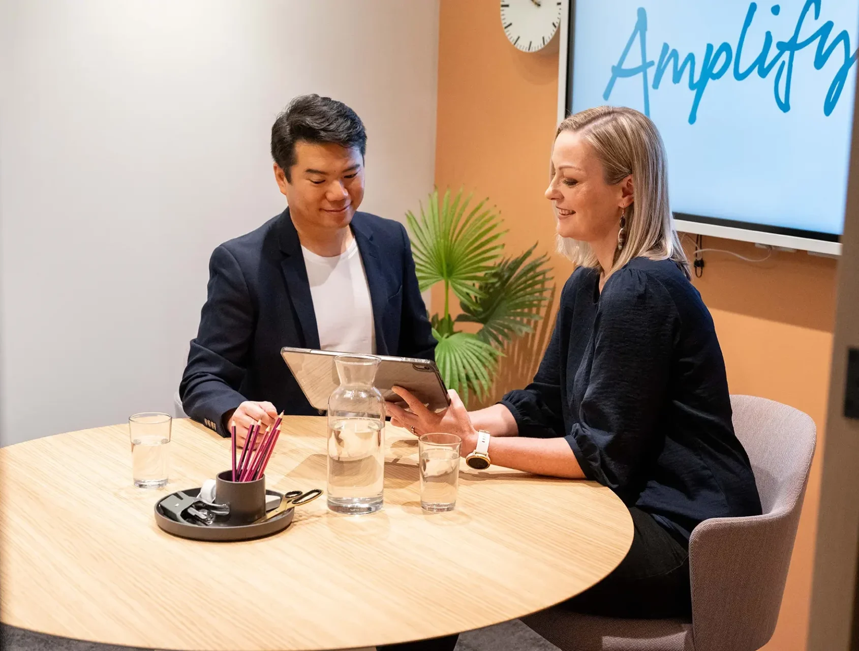 Two colleagues reviewing a tablet in a meeting room